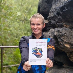 Autorka Wiolka Czuryńska w stroju sportowym prezentuje e-book „Zrób tylko jeden krok. Tom 1” na tle skał w Tiske Steny.