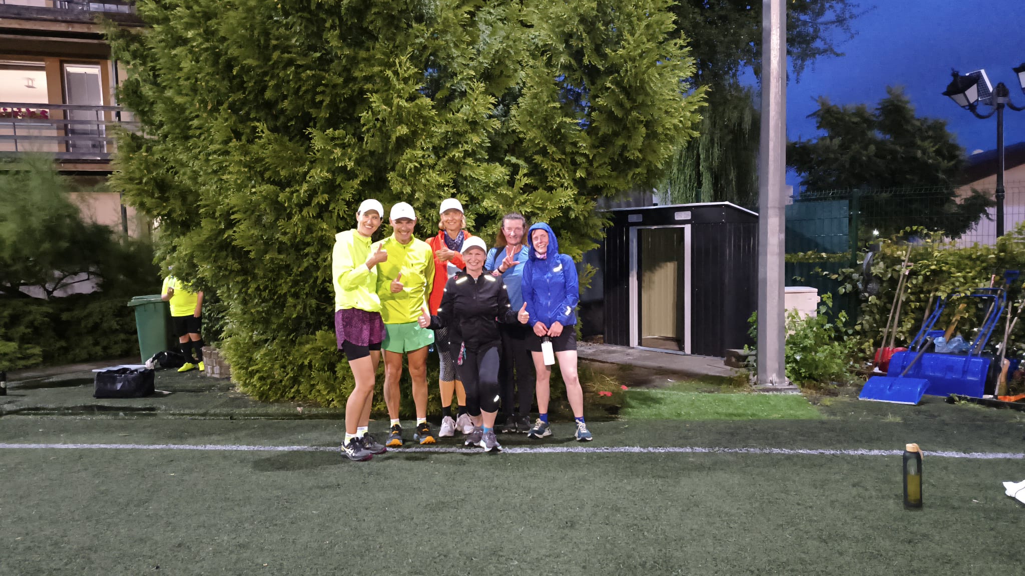 Uśmiechnięta grupa biegaczek i biegaczy Drużyny Pokochaj Bieganie po wieczornym treningu na boisku Centrum Sportowego Checz w Gdyni.